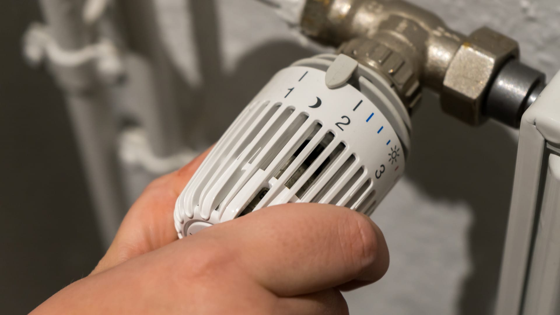 A hand turns the thermostat on a heater
